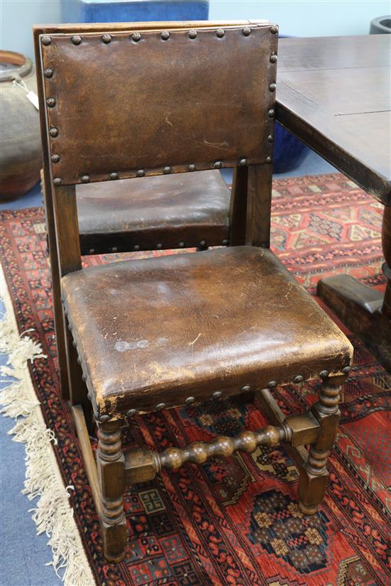 A set of eight Cromwellian style oak dining chairs upholstered in brass studded hide (two with arms)